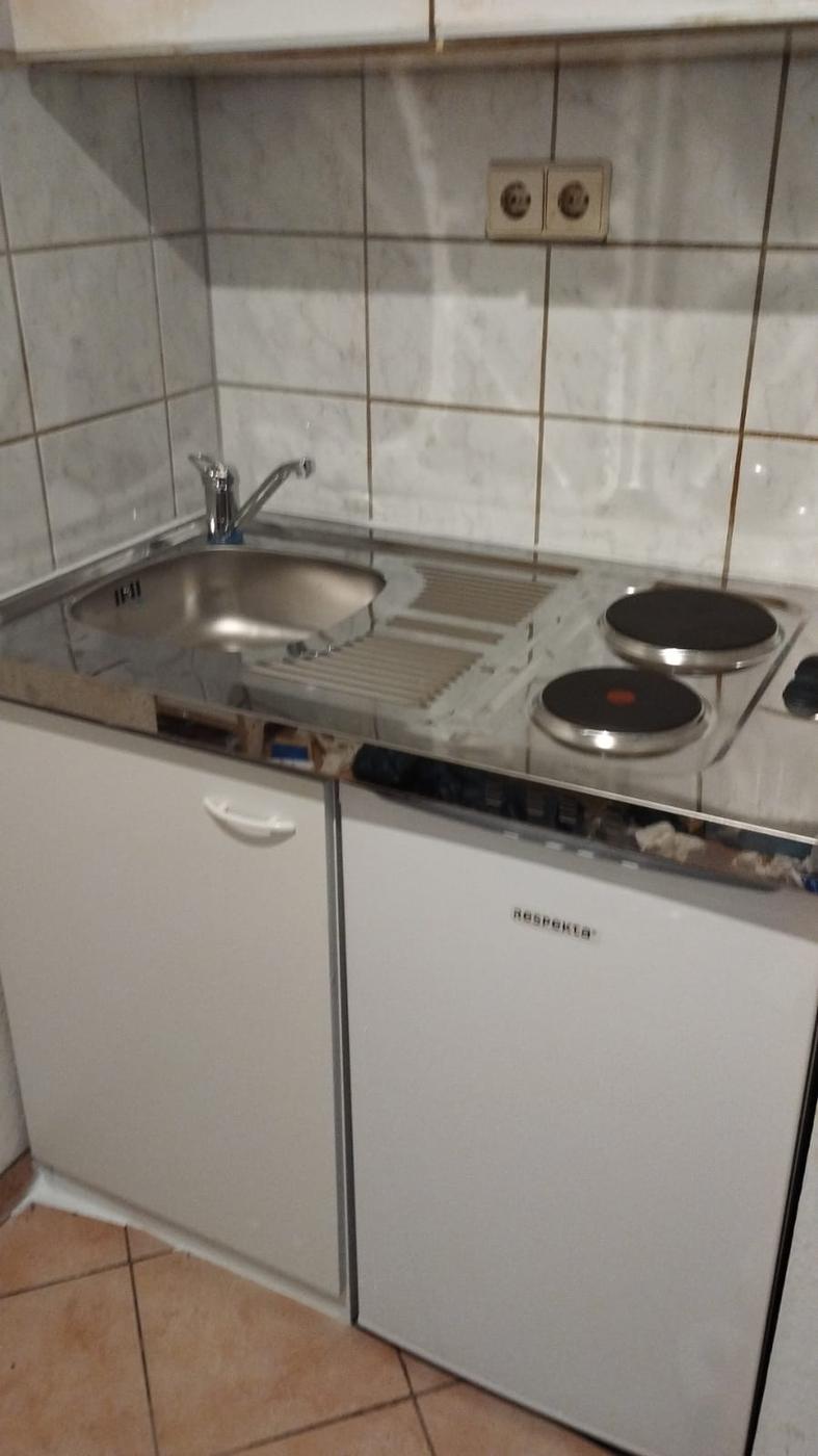 Küchenzeile mit Edelstahlspüle und zwei Kochplatten in einer Mietwohnung