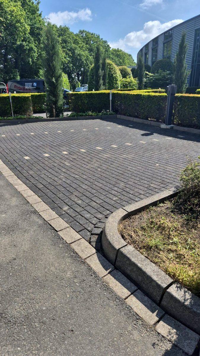 Gereinigte Pflasterfläche mit sauberer Kante vor einer Hecke